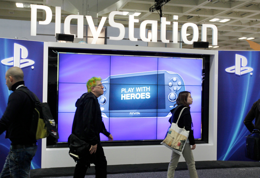 FILE- Attendees walking past the Sony PlayStation PS Vita console on display in the Sony PlayStation booth at the Game Developers Conference in San Francisco on March 8, 2012. (AP Photo/Paul Sakuma, File)