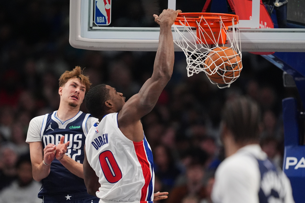 Detroit Pistons center Jalen Duren (0) dunks as Dallas Mavericks' Cooper Flagg (32) defends in the first half of an NBA basketball game in Dallas, Thursday, Dec. 18, 2025. (AP Photo/Tony Gutierrez)
