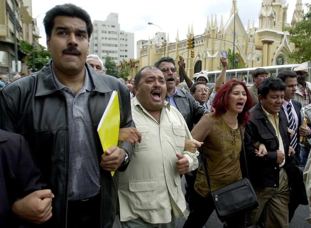 FILE - Pro-government lawmakers from left: Nicolas Maduro, Francisco Solorzano and Cilia Flores, surrounded by supporters, leave the National Congress building boycotting a parliamentary session, in Caracas, Venezuela, June 12, 2003. (AP Photo/Fernando Llano, File)