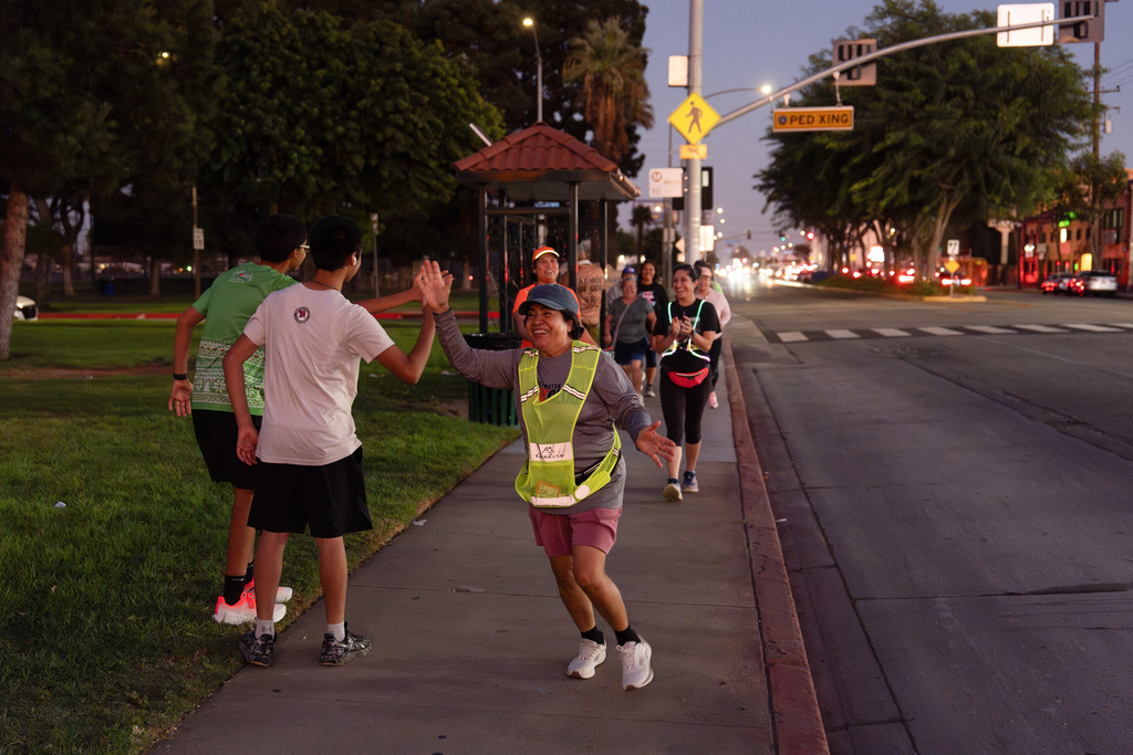 Rosa Abundiz, center, is greeted by fellow members of the Huntington Park Run Club after finishing the course in Huntington Park, Calif., Sept. 24, 2025. (AP Photo/Jae C. Hong)