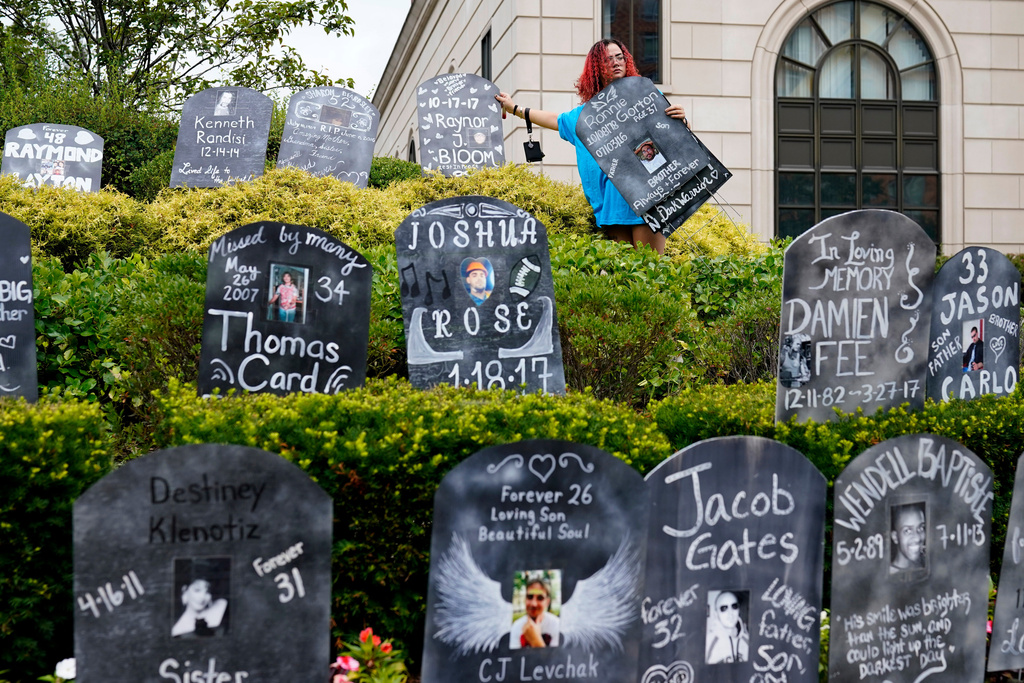FILE - Jayde Newton helps to set up cardboard gravestones with the names of victims of opioid abuse outside the courthouse where the Purdue Pharma bankruptcy is taking place in White Plains, N.Y., on Aug. 9, 2021. (AP Photo/Seth Wenig, File)
