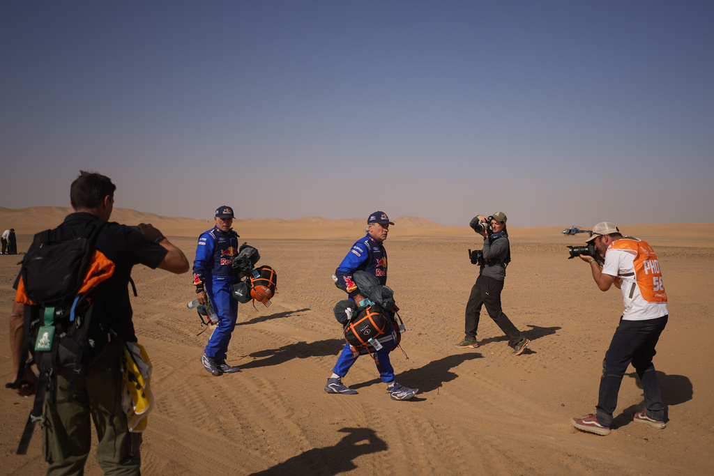 Journalists film driver Carlos Sainz, center, and co-driver Lucas Cruz at the end of the ninth stage of the Dakar Rally between Wadi Ad Dawasir and Bisha, Saudi Arabia, Tuesday, Jan.13, 2026. (AP Photo/Thibault Camus)