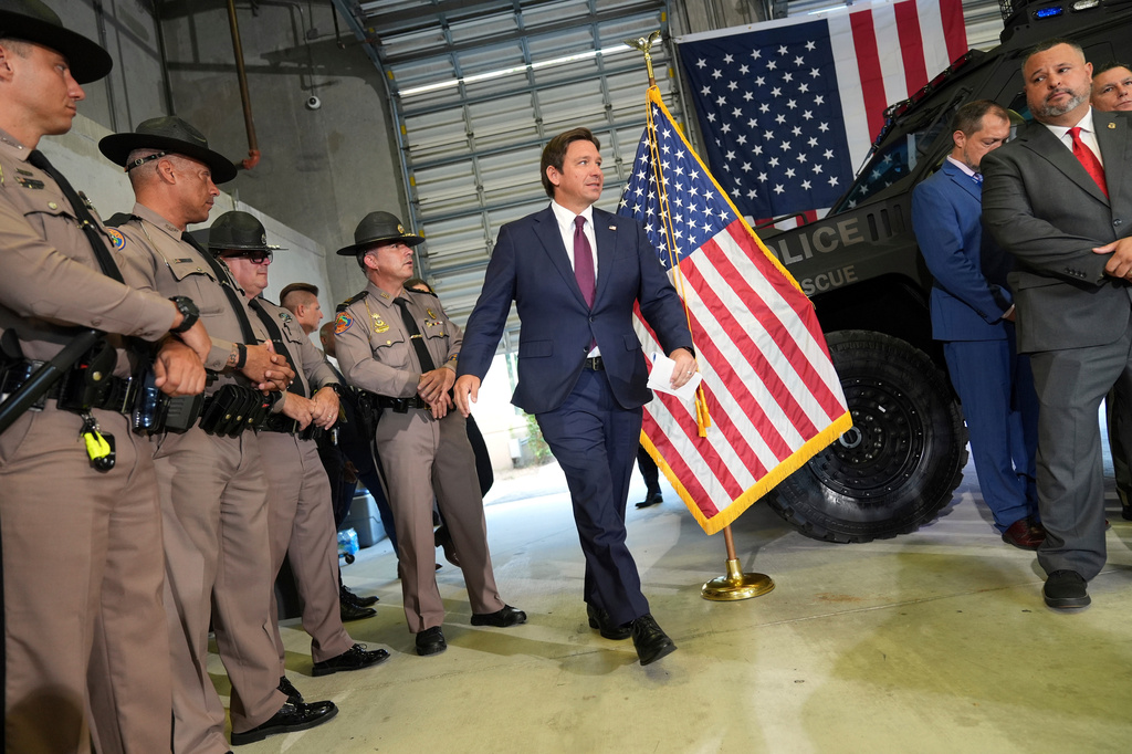 FILE - Florida Highway Patrol officers watch Gov. Ron DeSantis arrive at a press conference about a recent immigration enforcement operation, at the South Florida office of U.S. Immigration and Customs Enforcement and Enforcement and Removal Operations, May 1, 2025, in Miramar, Fla. (AP Photo/Rebecca Blackwell, File)