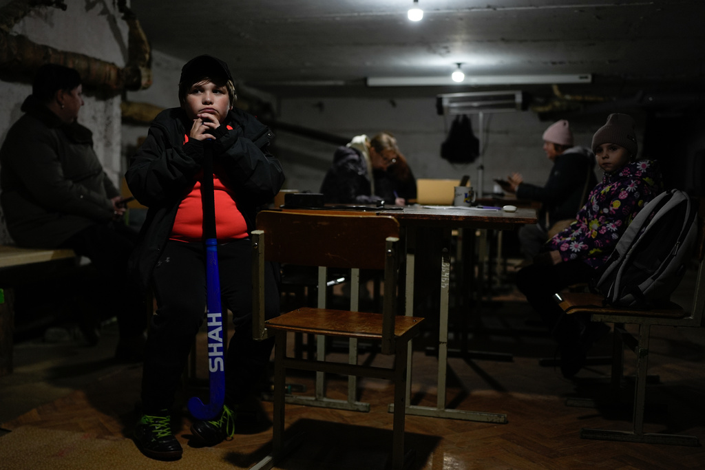 Tymofii Lifyrynko, 11, holds his hockey stick while waiting out an air raid alarm in an underground shelter, Thursday, Oct. 16, 2025, in Shostka, Ukraine. (AP Photo/Julia Demaree Nikhinson)