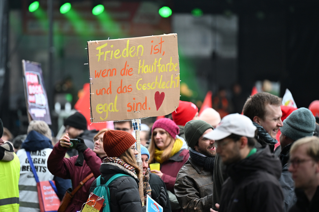 A demonstrator holds up a sign that reads: "Peace is when skin color and gender don't matter", as thousands gather in Giessen, Germany, Saturday Nov. 29, 2025, as the far-right Alternative for Germany’s new youth organization is set to kick off its founding convention. (Michael Brandt/dpa via AP)