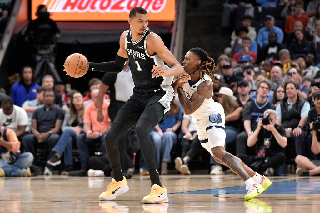 San Antonio Spurs forward Victor Wembanyama (1) handles the ball against Memphis Grizzlies guard Javon Small, right, in the first half of an NBA basketball game Wednesday, March 25, 2026, in Memphis, Tenn. (AP Photo/Brandon Dill)