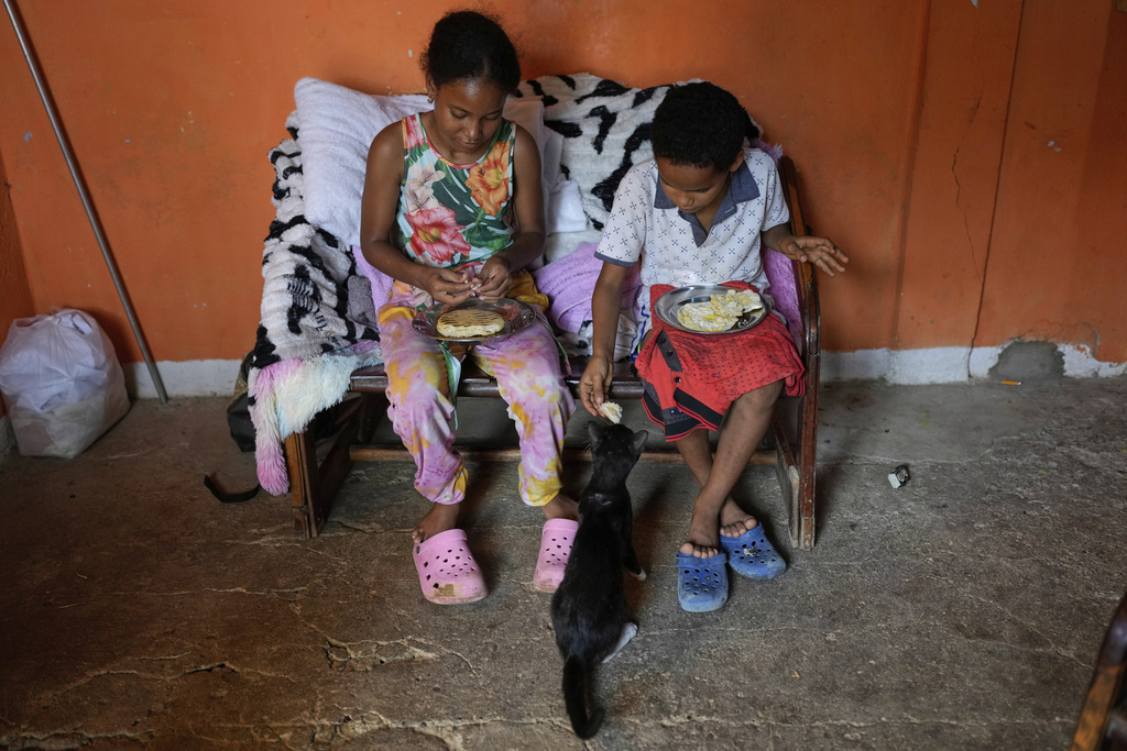 Siblings Lixandra Ramirez and her brother Elier Rojas eat cornmeal flatbread known as "arepas" for lunch at their home in Coro, Venezuela, Wednesday, June 25, 2025. (AP Photo/Ariana Cubillos)