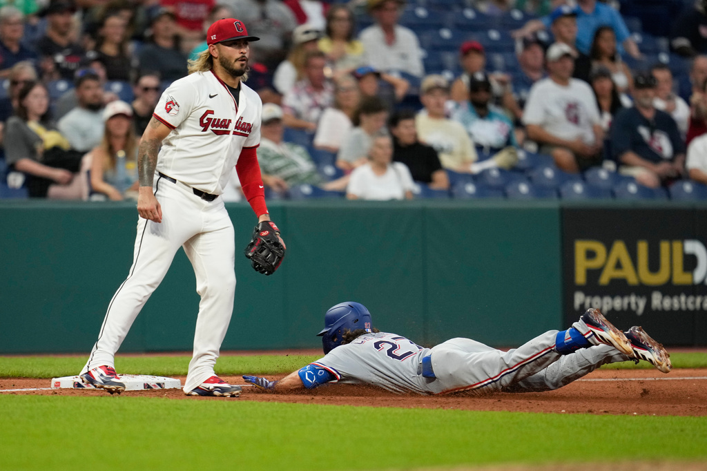 Texas Rangers' Cameron Cauley, right, slides into third base with a triple in front of Cleveland Guardians third baseman Gabriel Arias, left, in the seventh inning of a baseball game against the Cleveland Guardians in Cleveland, Monday, June 29, 2026. (AP Photo/Sue Ogrocki)