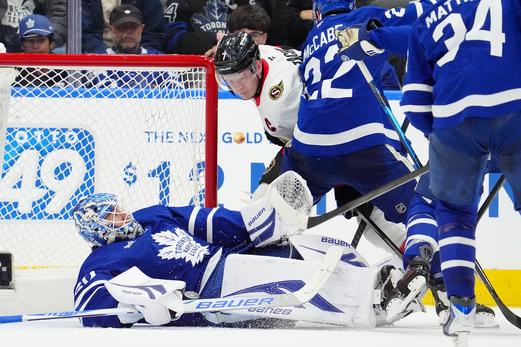 Ottawa Senators left wing Brady Tkachuk (7) knocks Toronto Maple Leafs goaltender Joseph Woll (60) to the ice during the second period of an NHL hockey game in Toronto, Saturday, Dec. 27, 2025. (Frank Gunn/The Canadian Press via AP)