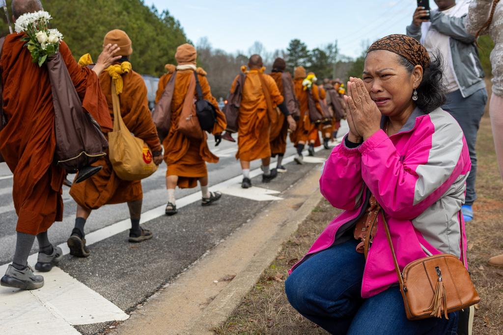A woman reacts as Buddhist monks on a "Walk for Peace" walk on Veterans Parkway in Fayetteville, Ga., on Monday, Dec. 29, 2025, from Texas to Washington, D.C. (Arvin Temkar/Atlanta Journal-Constitution via AP)