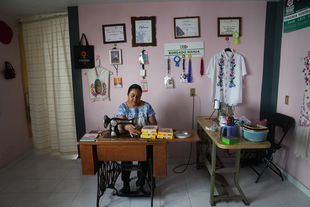Virginia Veronica Arce Arce, a designer of Nahua folk art embroidery worn by Mexican President Claudia Sheinbaum, works in her workshop at home in the municipality of San Isidro Buen Suceso, Tlaxcala, Mexico, Friday, Dec. 12, 2025. (AP Photo/Marco Ugarte)