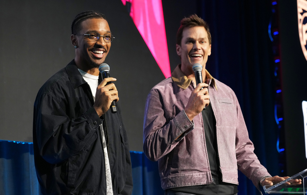 NFL quarterback Jayden Daniels, left, and Tom Brady speak from the stage at the launch party for Fanatics Studio, a global studio for sports entertainment, on Tuesday, Jan. 13, 2026, at the Intuit Dome in Inglewood, Calif. (AP Photo/Chris Pizzello)