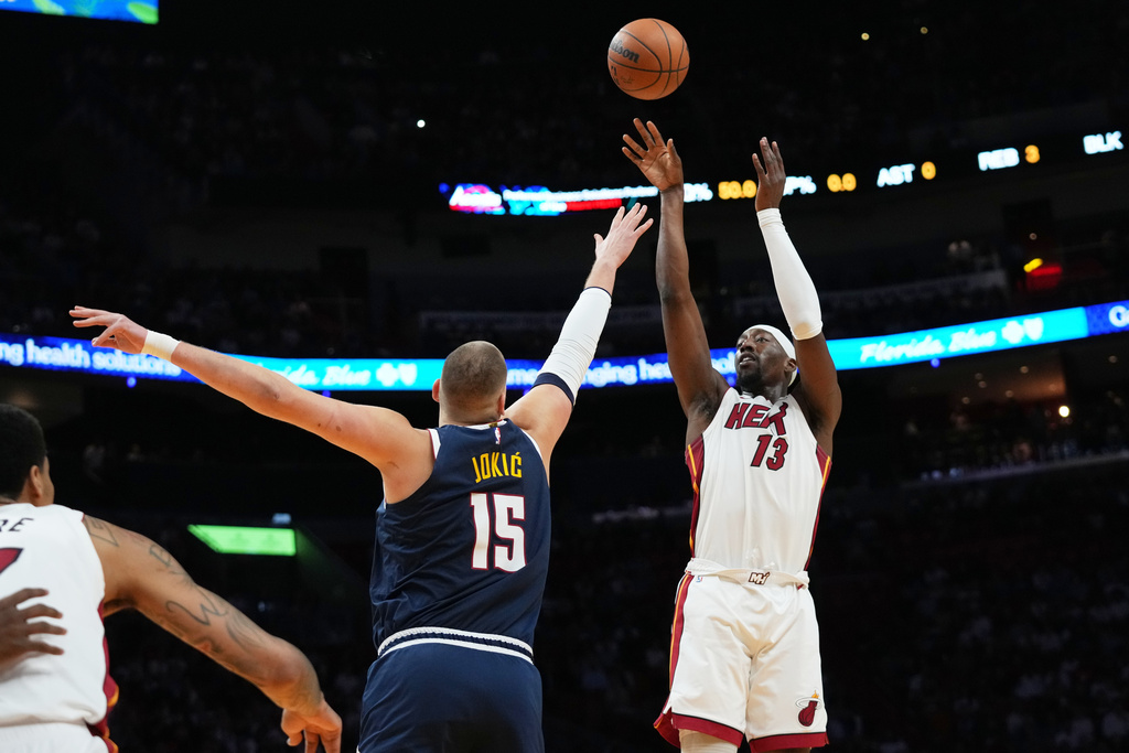Miami Heat center Bam Adebayo (13) shoots over Denver Nuggets center Nikola Jokic (15) during the first half of an NBA basketball game, Monday, Dec. 29, 2025, in Miami. (AP Photo/Lynne Sladky)