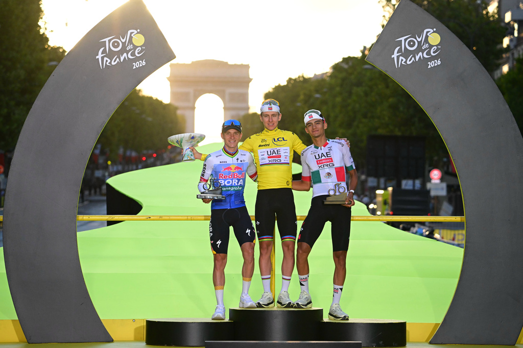 Slovenia's Tadej Pogacar, wearing the overall leader's yellow jersey, celebrates on the podium after winning the Tour de France cycling race alongside Belgium's Remco Evenepoel, second, and Mexico's Isaac Del Toro, third, in Paris, Sunday, July 26, 2026. (AP Photo/Bernard Papon/Pool Photo via AP)