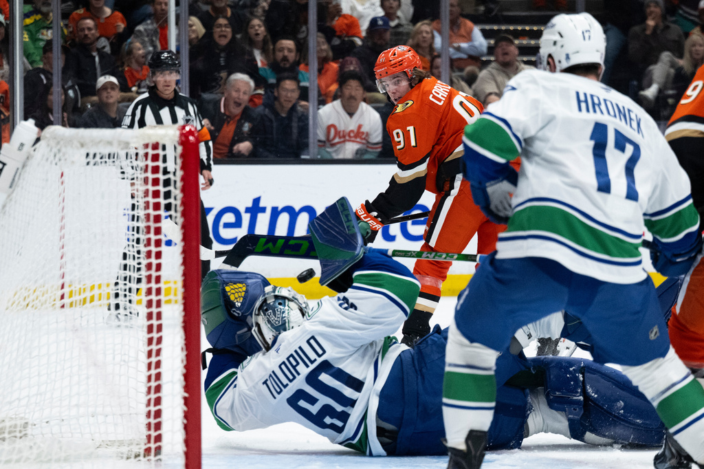 Anaheim Ducks center Leo Carlsson, top, scores past Vancouver Canucks goaltender Nikita Tolopilo during the third period of an NHL hockey game, Sunday, April 12, 2026, in Anaheim, Calif. (AP Photo/Kyusung Gong)