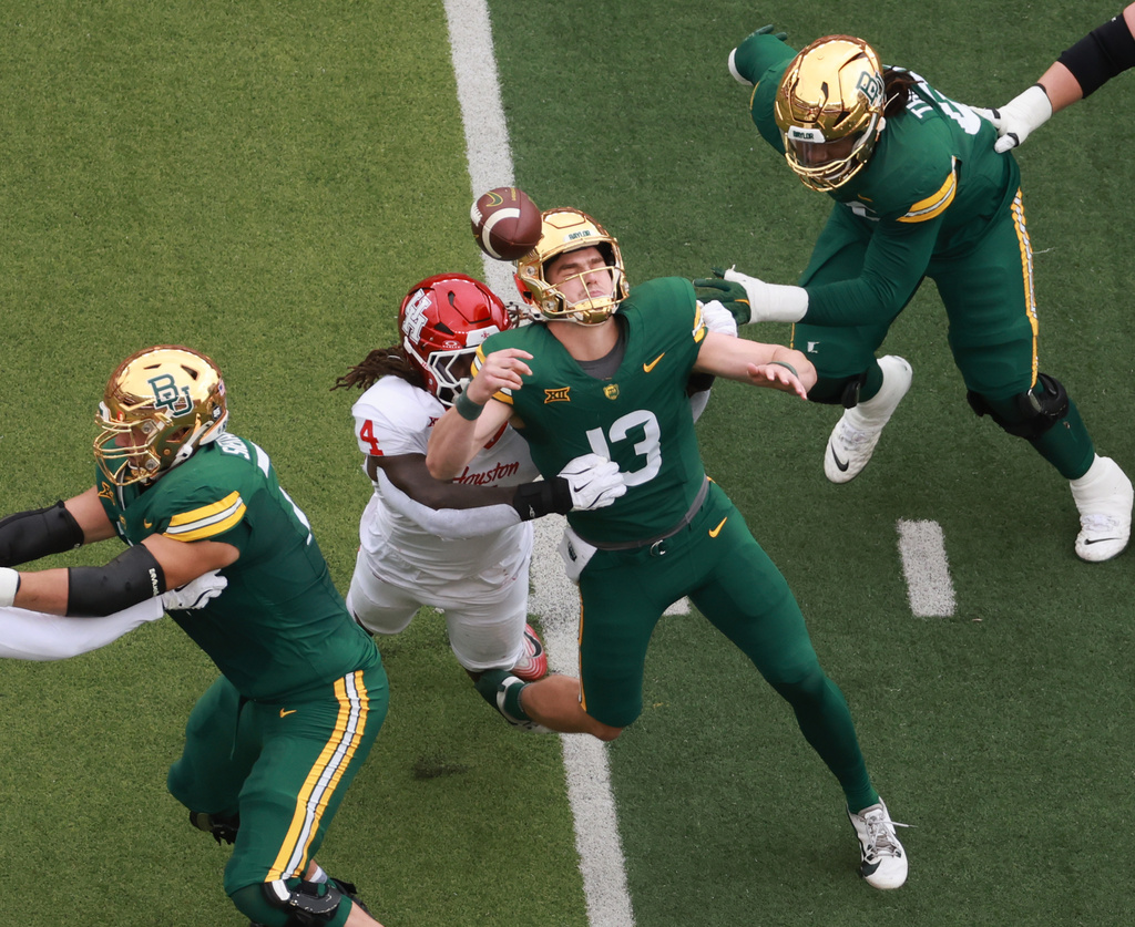 Baylor quarterback Sawyer Robertson fumbles the ball after getting hit by Houston defensive end Brandon Mack in the first half of an college football game, Saturday, Nov. 29, 2025, in Waco, Texas. (Rod Aydelotte/Waco Tribune-Herald via AP)