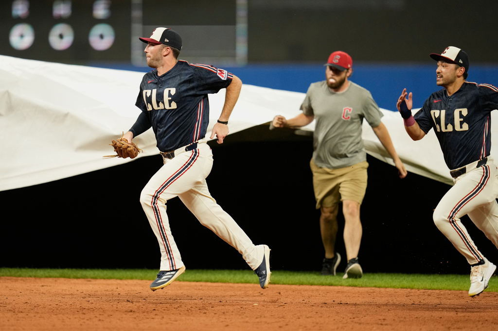 Cleveland Guardians left fielder David Fry, left, adnd center fielder Steven Kwan, right, run off the field as the grounds crew places the tarp ofthe field as a storm arrives in the fifth inning of a baseball game between the Chicago White Sox and the Cleveland Guardians in Cleveland, Friday, July 3, 2026. (AP Photo/Sue Ogrocki)