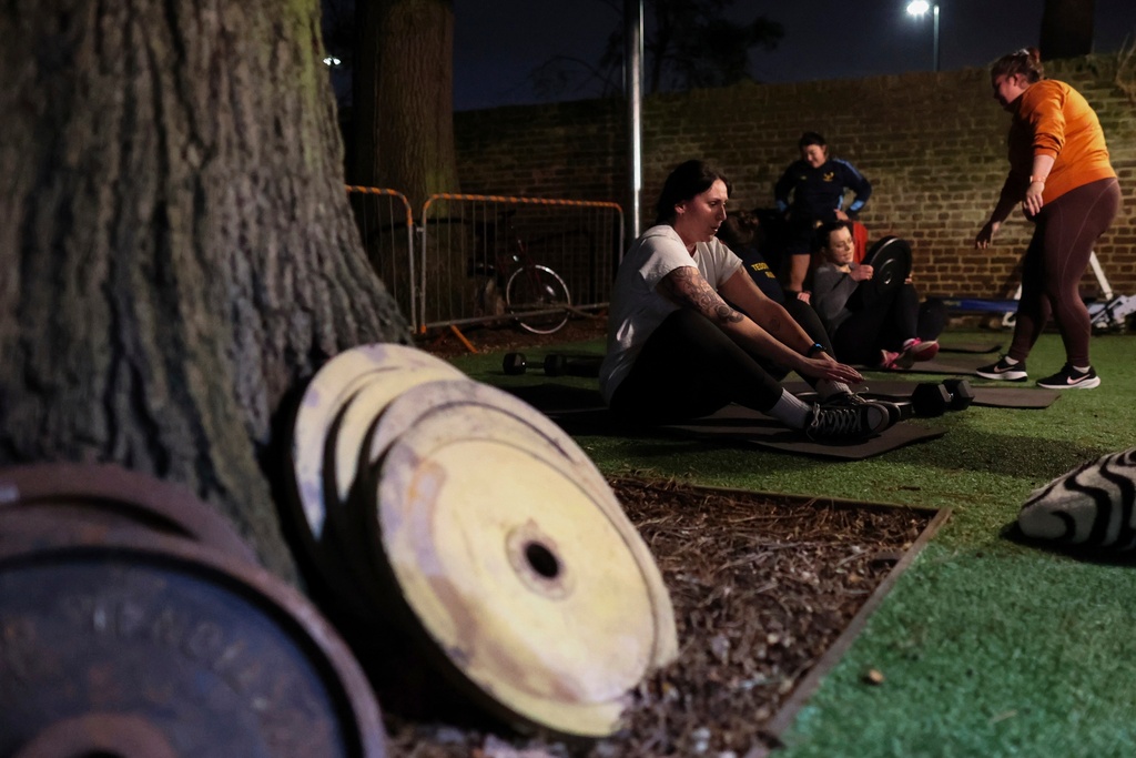 FILE - Chloe Spriggs, left, takes a moment as members of Teddington women's rugby team use weights as they train at the club house in Bushy Park in London, Thursday, Jan. 16, 2025. (AP Photo/Charlotte Coney,File)b