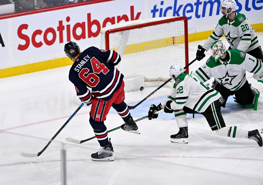 Winnipeg Jets' Logan Stanley (64) scores on Dallas Stars' goaltender Casey DeSmith (1) during the third period of their NHL hockey game in Winnipeg, Tuesday, Dec. 9, 2025. (Fred Greenslade/The Canadian Press via AP)