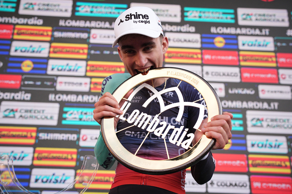 France's Paul Seixas bites thew trophy after winning Il Lombardia, Tour of Lombardy cycling race, in Como, Italy, Saturday, Oct. 10, 2026. (Marco Alpozzi/LaPresse via AP)