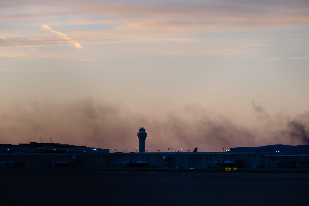 The ATC tower is seen while smoke rises from the crash site of UPS Flight 2796 near Louisville Muhammad Ali International Airport on Wednesday, Nov. 5, 2025, in Louisville, Ky. (AP Photo/Jon Cherry)