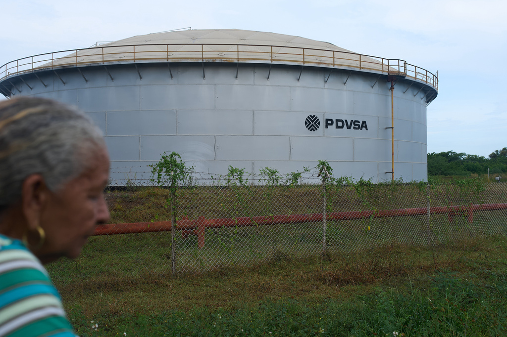 A woman walks near of a oil storage tank of Venezuela's state-run oil company, PDVSA in Cabimas, Venezuela, Tuesday, Sep. 1, 2026. (AP Photo/Ariana Cubillos)