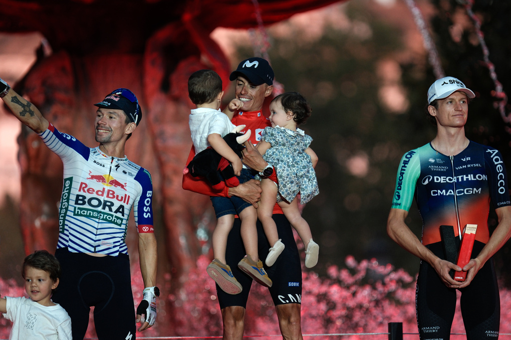 Spain's Enric Mas, center, celebrates on the podium after winning the overall classification of the Spanish Vuelta cycling race, flanked by second-place Slovenia's Primoz Roglic, left, and third-place Austria's Felix Gall, right, in Granada, Spain, Sunday, Sept. 13, 2026. (AP Photo/Gregorio Marrero)