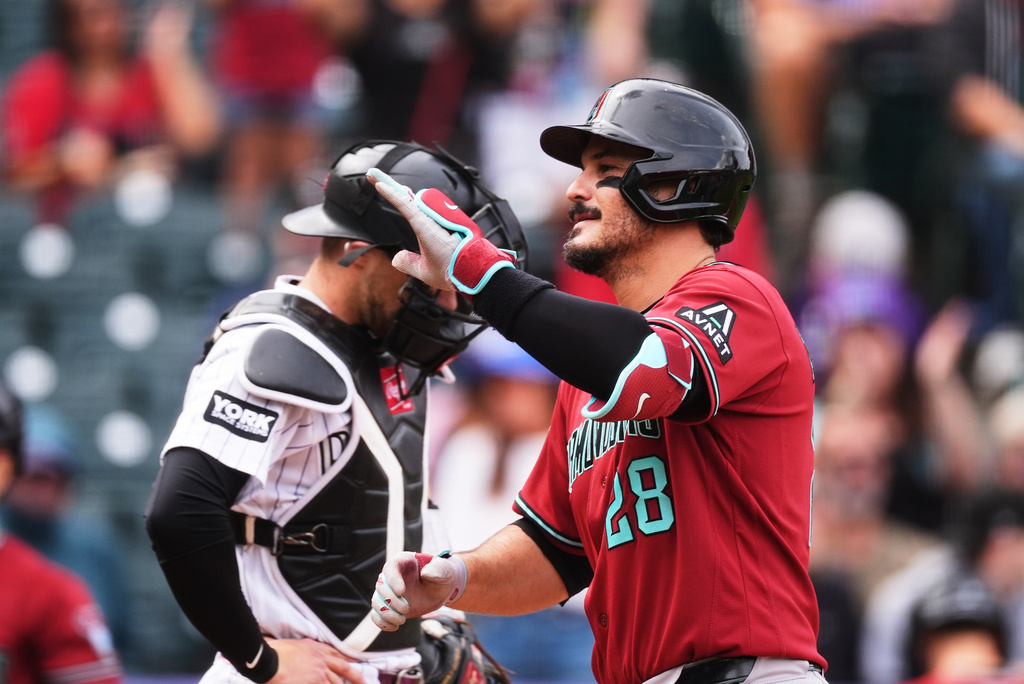 Arizona Diamondbacks' Nolan Arenado, front, gestures as he crosses home plate after hitting a two-run home run as Colorado Rockies catcher Brett Sullivan waits for play to resume in the first inning of a baseball game Thursday, Sept. 24, 2026, in Denver. (AP Photo/David Zalubowski)