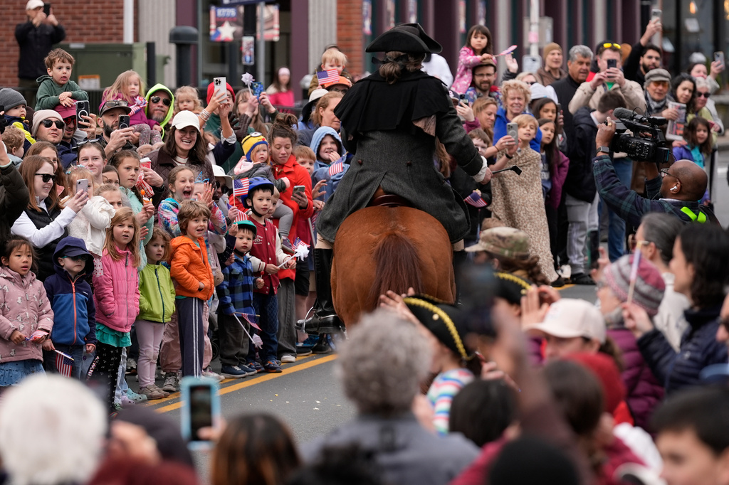 A large crowd watches the arrival of Brig. Gen. Richard Reale, dressed as American patriot Paul Revere, reenacts the 1775 Boston-to-Lexington ride to alert colonists of approaching British troops, Monday, April 20, 2026, in Medford, Mass.. (AP Photo/Robert F. Bukaty)