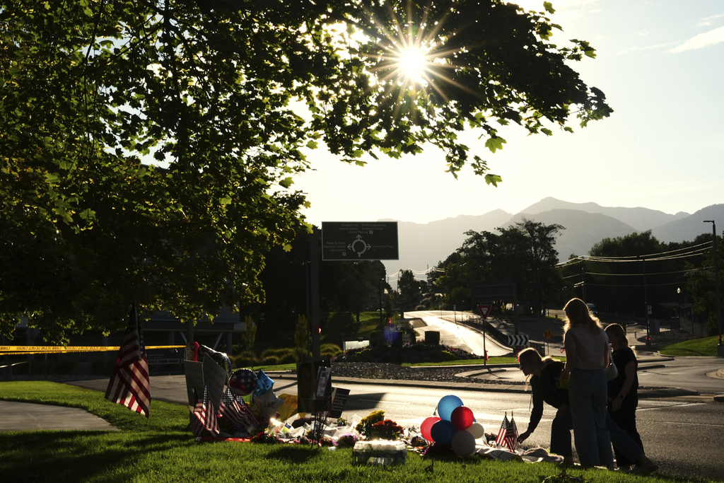 Women place flowers at a memorial outside Utah Valley University after Turning Point USA CEO and co-founder Charlie Kirk was shot and killed, Saturday, Sept. 13, 2025, in Orem, Utah. (AP Photo/Lindsey Wasson)