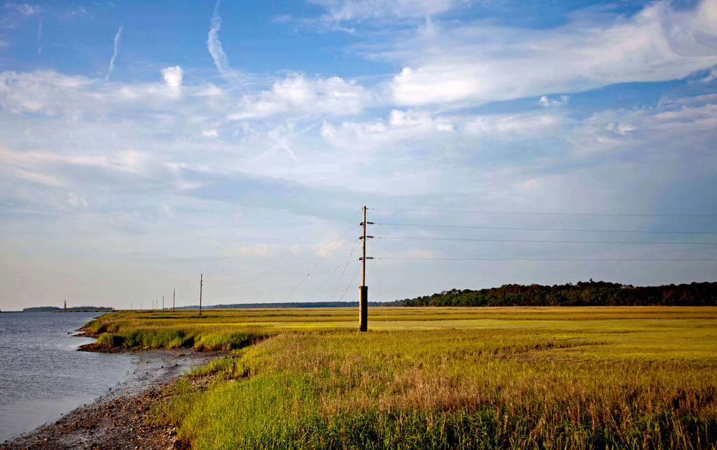 FILE - A utility pole stands in the middle of a marsh at sunset on Sapelo Island, Ga., on May 16, 2013. (AP Photo/David Goldman, File)