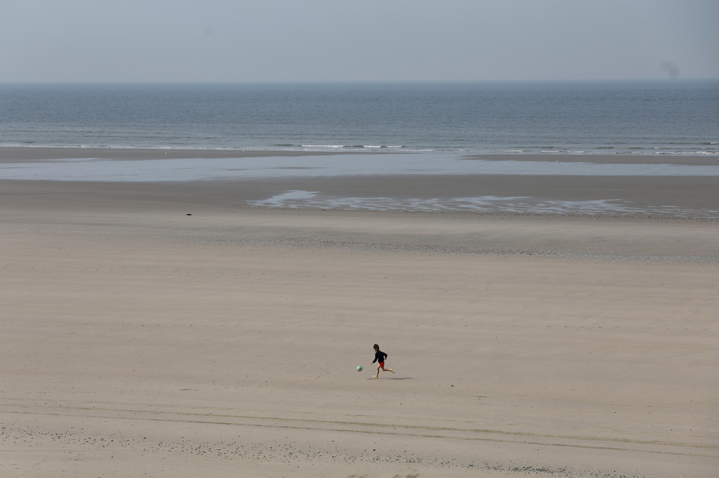 A young boy runs on the beach after at least four people died while trying to board an inflatable boat for a dangerous sea crossing from northern France to the U.K. in Equihen-Plage, northern France. Thursday, April 9, 2026. (AP Photo/Jean-Francois Badias)