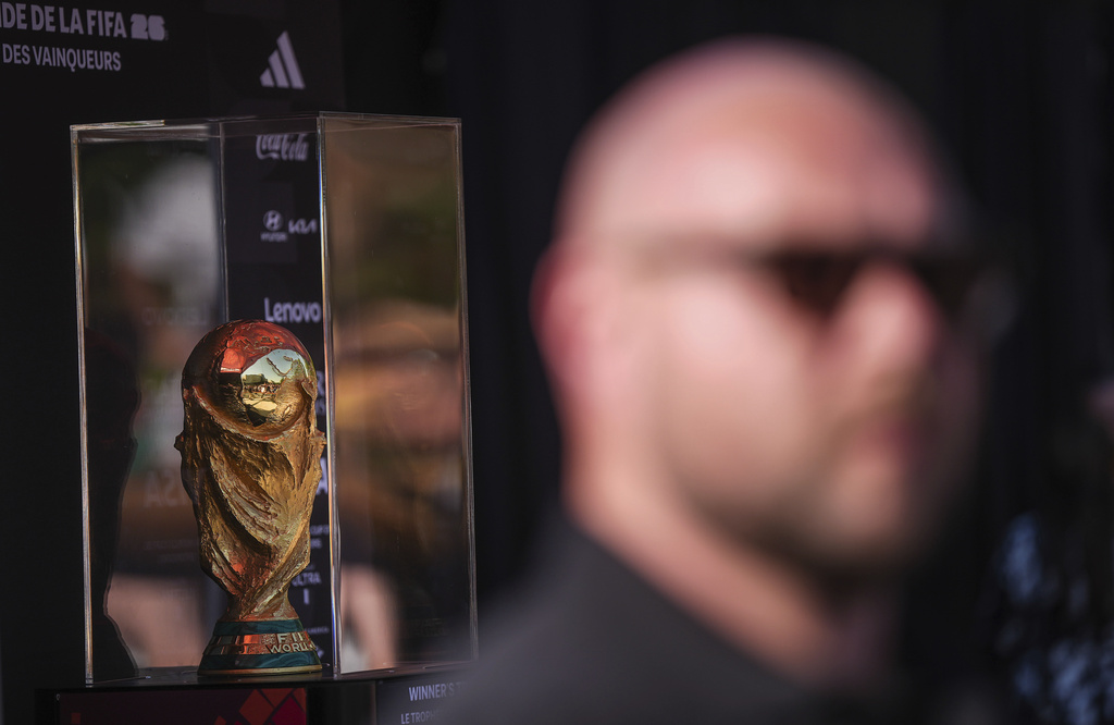 A security official stands nearby as the FIFA World Cup winner's trophy is displayed in a transparent box under a tent, during an event for fans to view it at the Italian Cultural Center in Vancouver, British Columbia, Tuesday, Aug. 26, 2025. (Darryl Dyck/The Canadian Press via AP)