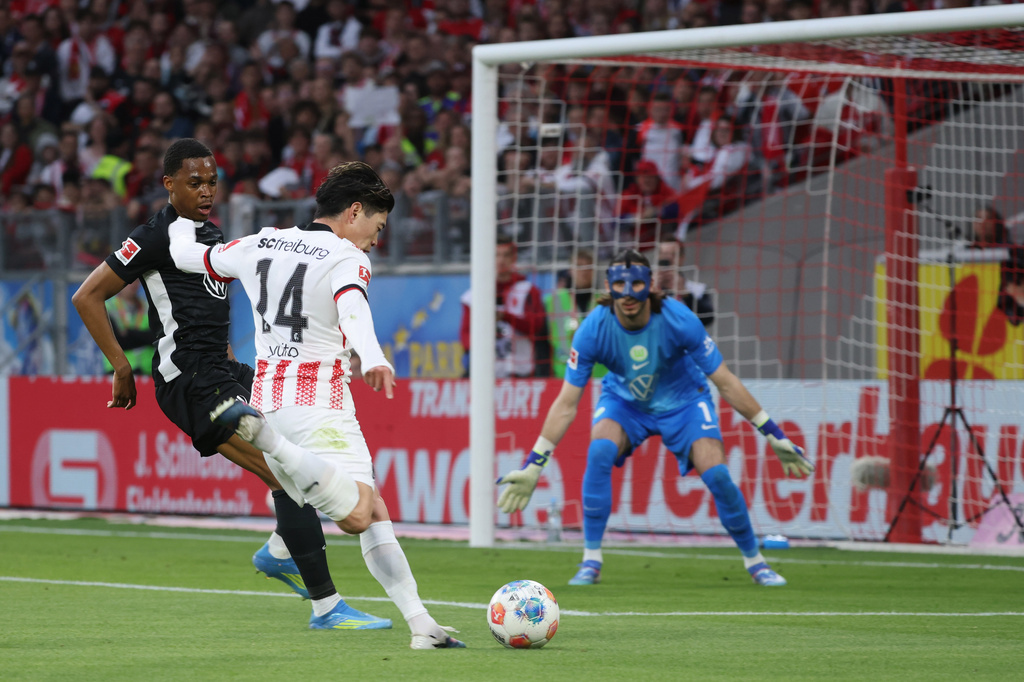 Yuito Suzuki, centre, challenged for the ball with Wolfsburg's Jeanuël Belocian, left, and goalkeeper Kamil Grabara during the German Bundesliga soccer match between SC Freiburg and VfL Wolfsburg in Freiburg im Breisgau, Germany, Sunday, May 3, 2026. (Philipp von Ditfurth/dpa via AP)