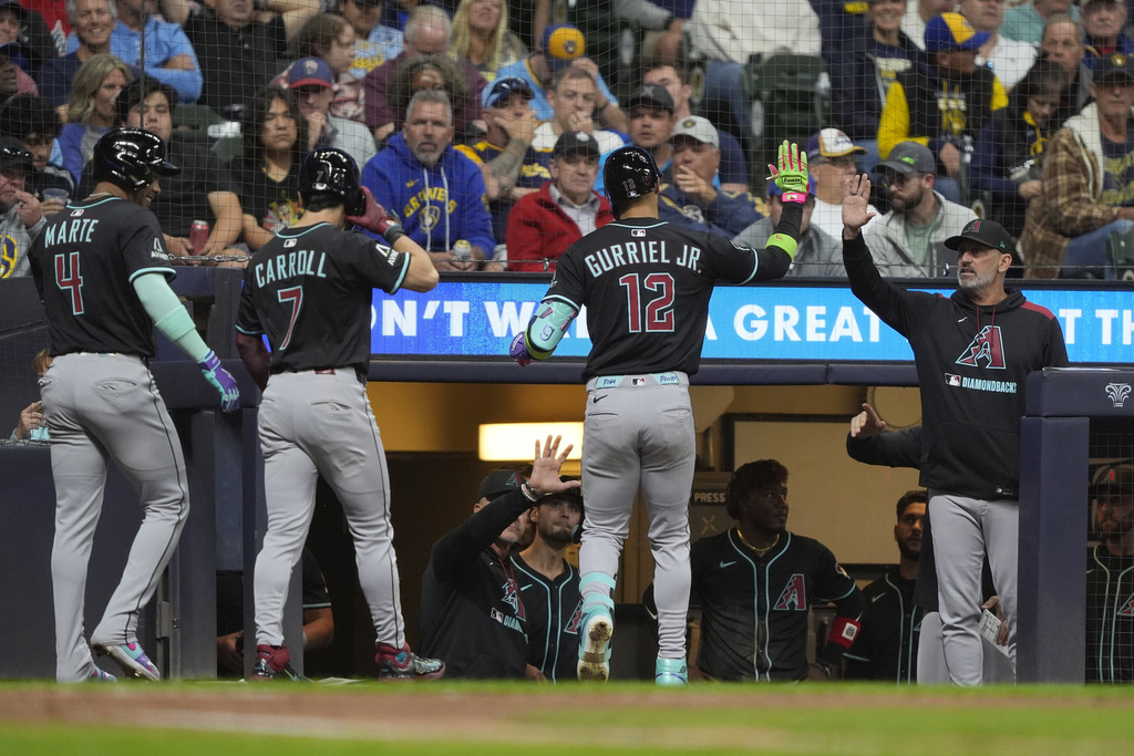 Arizona Diamondbacks' Lourdes Gurriel Jr. (12) is congratulated at the dugout after hitting a three-run home run during the fifth inning of a baseball game against the Milwaukee Brewers, Monday, Aug. 25, 2025, in Milwaukee. (AP Photo/Aaron Gash)