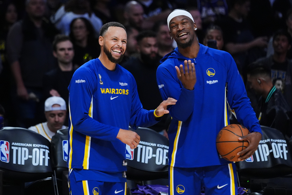 Golden State Warriors guard Stephen Curry, left, smiles next to forward Jimmy Butler III before an NBA basketball game against the Los Angeles Lakers Tuesday, Oct. 21, 2025, in Los Angeles. (AP Photo/Ethan Swope)