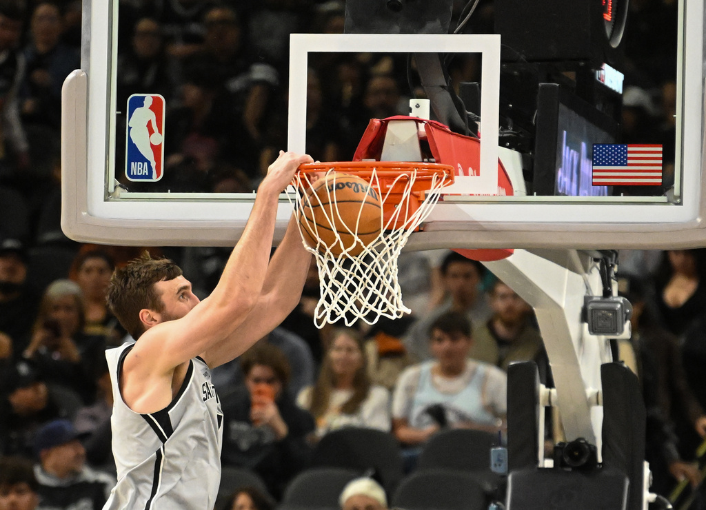 San Antonio Spurs center Luke Kornet dunks the ball against the Washington Wizards during the first half of an NBA basketball game in San Antonio, Thursday, Dec. 18, 2025. (AP Photo/Billy Calzada)