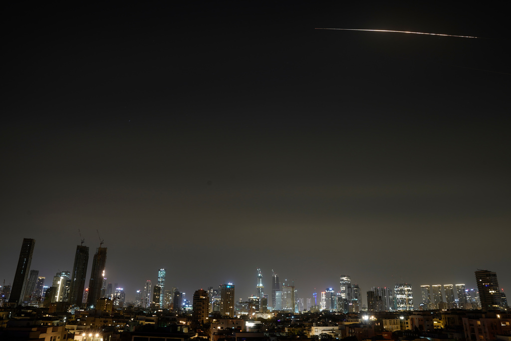 The remains of an Iranian missile cross the sky over Tel Aviv after being intercepted early Saturday, March 21, 2026. (AP Photo/Maya Levin)