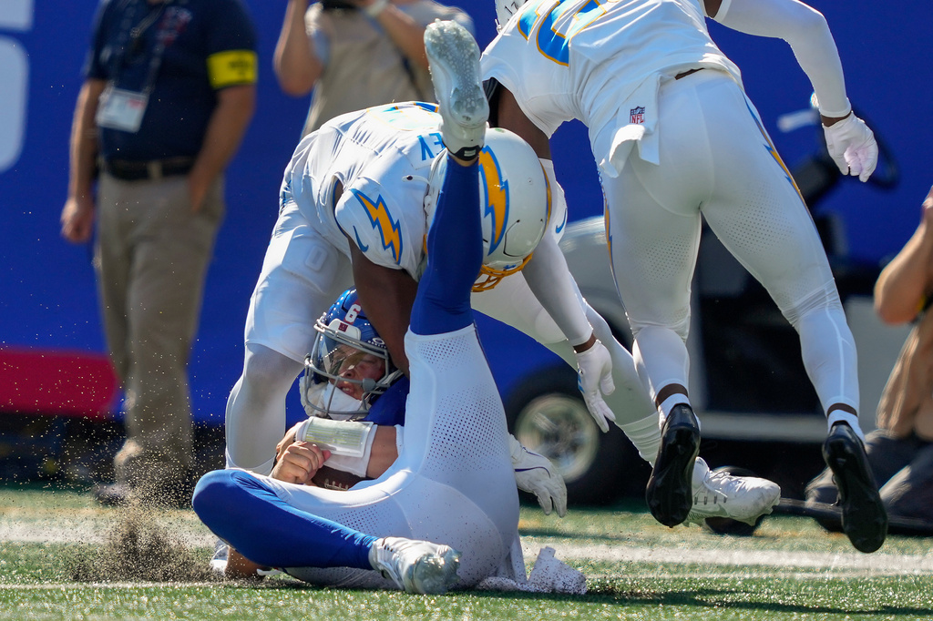 New York Giants quarterback Jaxson Dart (6) is tackled by Los Angeles Chargers cornerback Cam Hart (20) and linebacker Daiyan Henley (0) during the third quarter of an NFL football game, Sunday, Sept. 28, 2025, in East Rutherford, N.J. (AP Photo/Yuki Iwamura)
