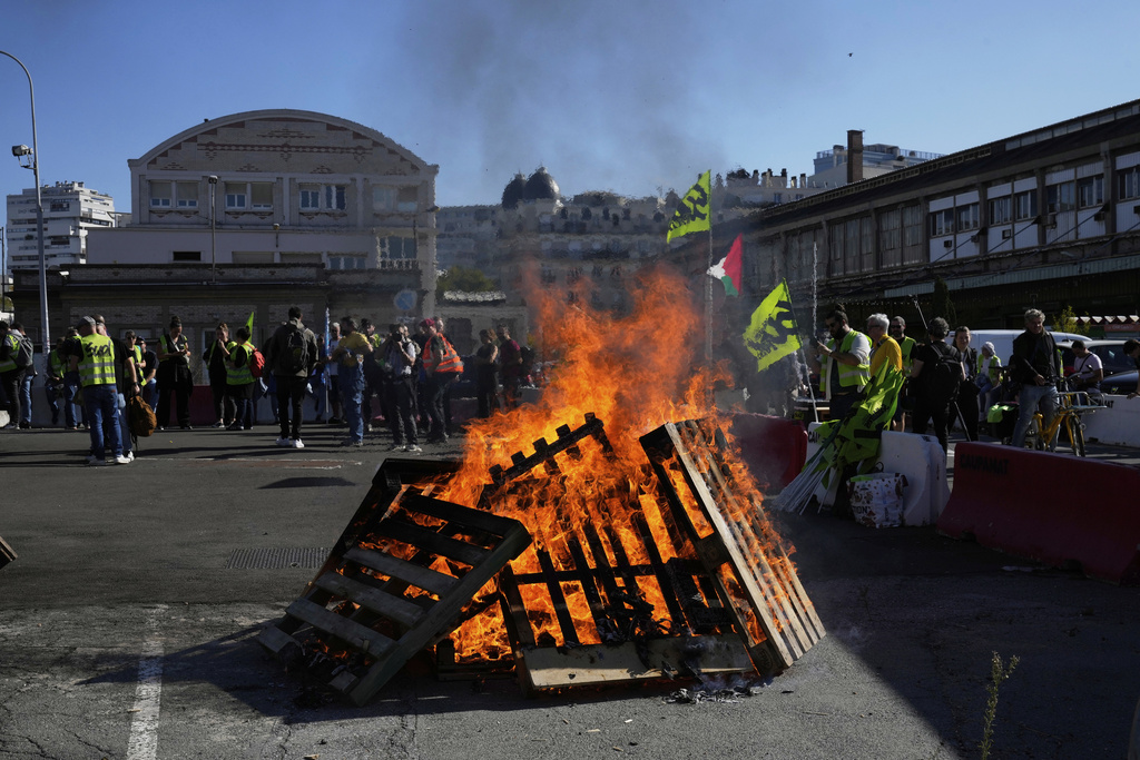 Workers gather next wooden pallets on fire at the Gare de Lyon train station during a protest called by major trade unions to oppose budget cuts, in Paris, France, Thursday, Sept. 18, 2025. (AP Photo/Michel Euler)