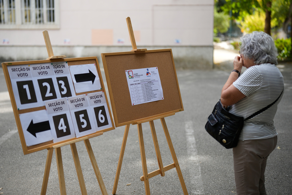 A woman checks where to vote at a polling station for Portugal's municipal elections in Lisbon, Sunday, Oct. 12, 2025. (AP Photo/Armando Franca)