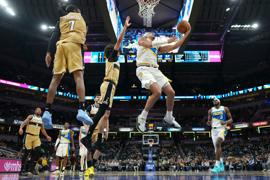 Indiana Pacers guard Andrew Nembhard, right, shoots in front of Washington Wizards guard Bub Carrington during the first half of an NBA basketball game in Indianapolis, Sunday, Dec. 14, 2025. (AP Photo/AJ Mast)