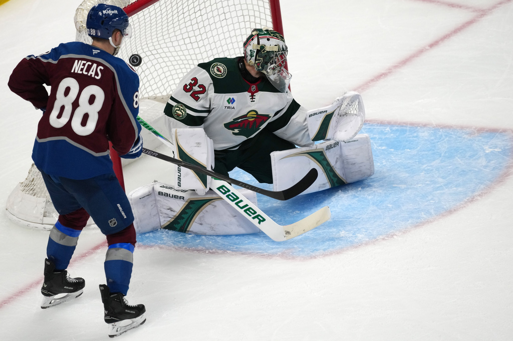 Colorado Avalanche center Martin Necas, left, looks on as Minnesota Wild goaltender Filip Gustavsson allows a goal by Colorado center Nathan MacKinnon in the third period of Game 2 of an NHL hockey Stanley Cup second-round playoff series Tuesday, May 5, 2026, in Denver. (AP Photo/David Zalubowski)