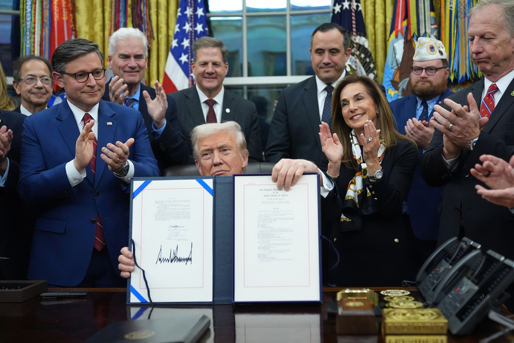 President Donald Trump displays the signed funding bill to reopen the government, in the Oval Office of the White House, Wednesday, Nov. 12, 2025, in Washington. (AP Photo/Jacquelyn Martin)