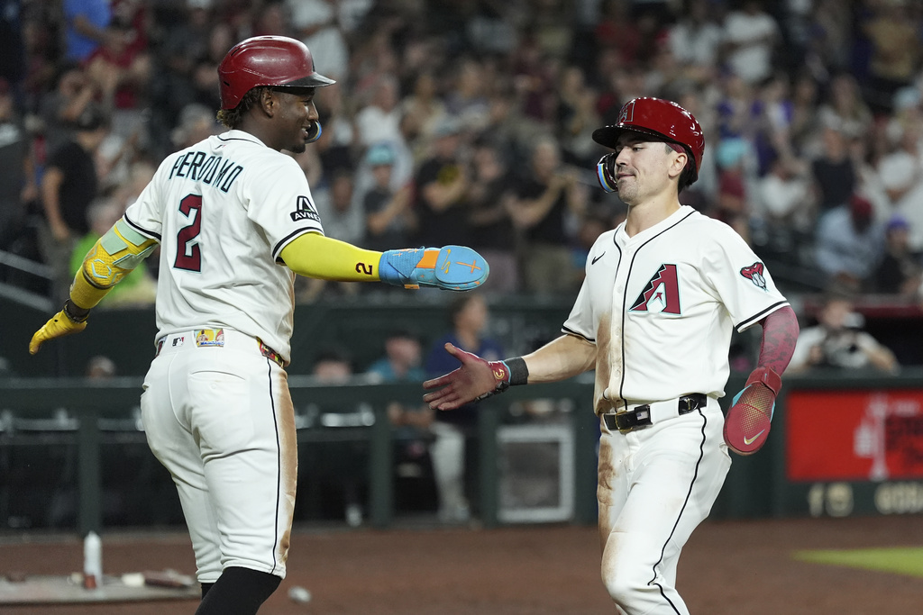 Arizona Diamondbacks' Geraldo Perdomo (2) and Corbin Carroll celebrate their runs scored against the Cleveland Guardians during the seventh inning of a baseball game Tuesday, Aug. 19, 2025, in Phoenix. (AP Photo/Ross D. Franklin)
