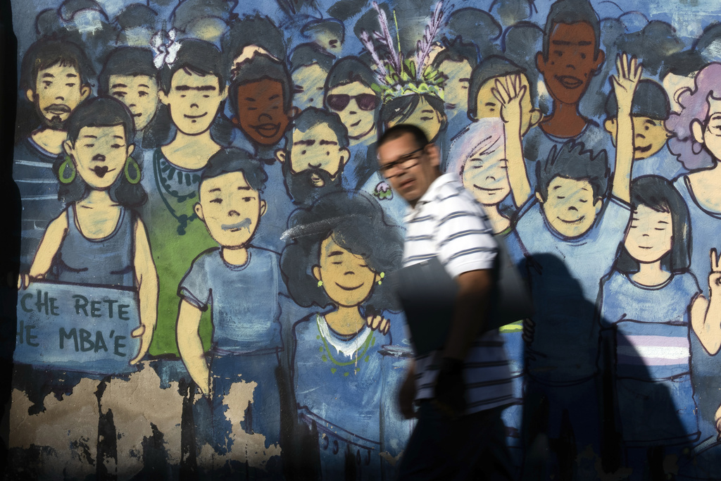 A pedestrian passes a mural that rads in the Guarani language "Che rete, che mba'e" which means "My body is mine" in Asuncion, Friday, Aug. 22, 2025. (AP Photo/Jorge Saenz)