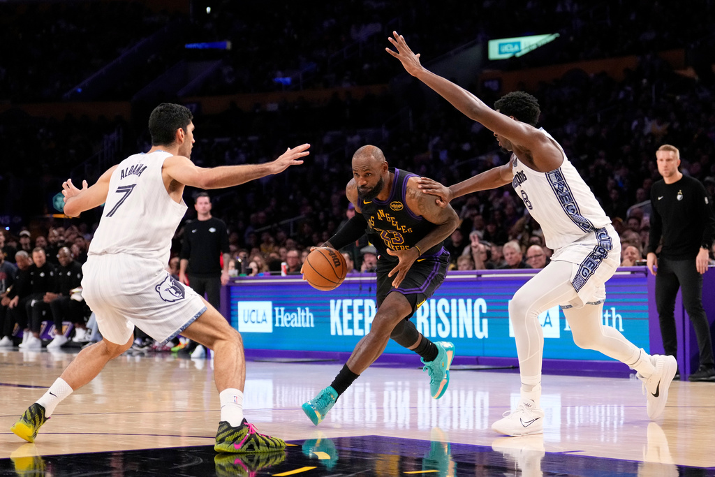 Los Angeles Lakers forward LeBron James, center, drives toward the basket as Memphis Grizzlies forward Santi Aldama, left, and forward Jaren Jackson Jr. defend during the second half of an NBA basketball game Friday, Jan. 2, 2026, in Los Angeles. (AP Photo/Mark J. Terrill)