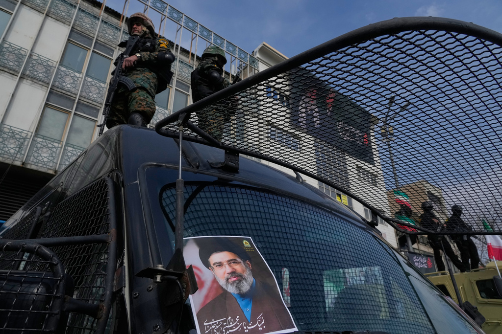 A poster of Ayatollah Mojtaba Khamenei, the successor to his late father Ayatollah Ali Khamenei as supreme leader is placed on an anti-riot police car as policemen stand on top of the car, during a rally to support him in Tehran, Iran, Monday, March 9, 2026. (AP Photo/Vahid Salemi)