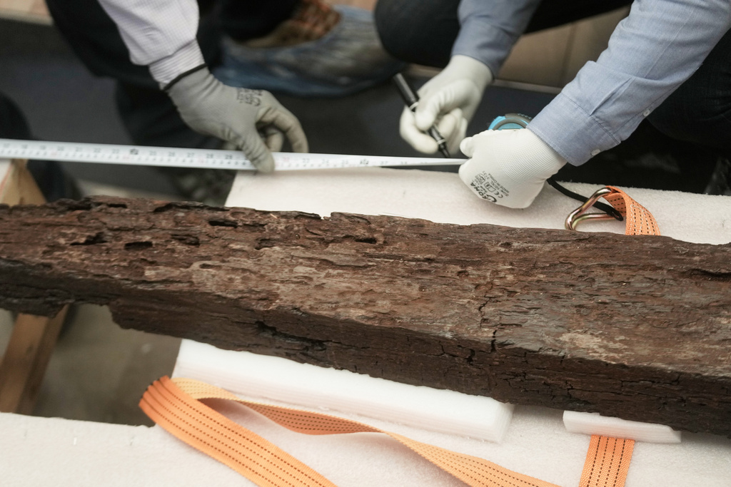 Archeologists measure an ancient wooden block as they prepare to reassemble the second solar boat of King Khufu, at the Grand Egyptian Museum in Giza, Egypt, Tuesday, Dec. 23, 2025. (AP Photo/Amr Nabil)