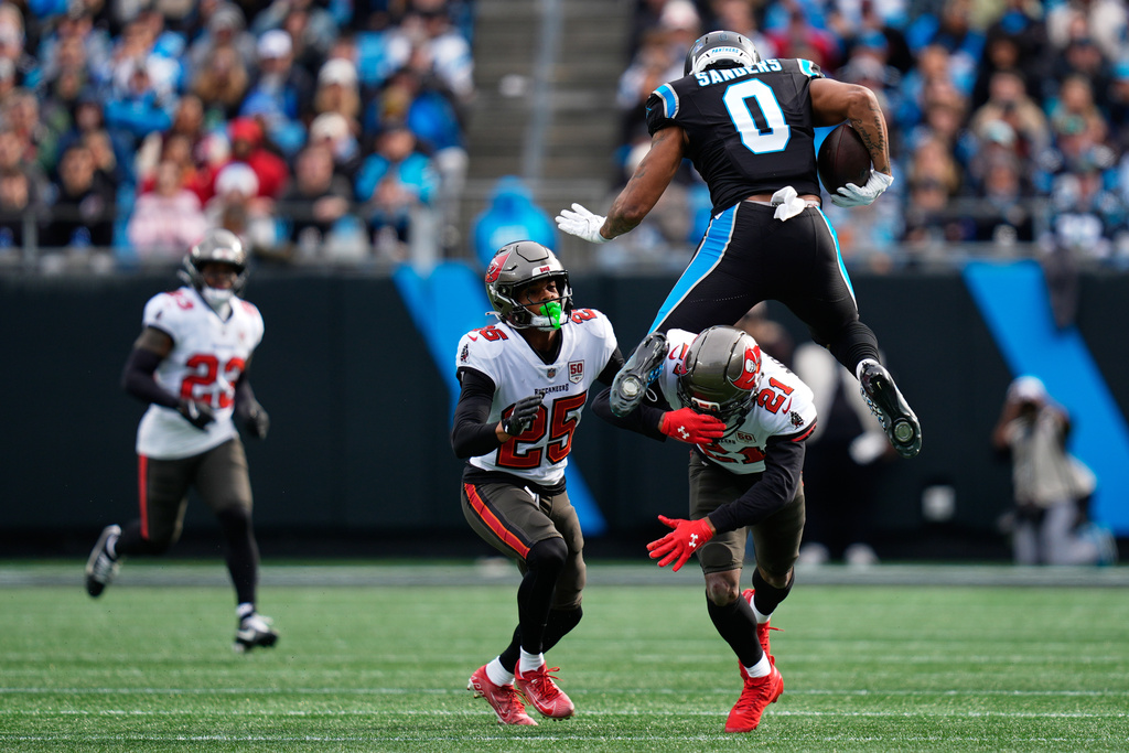 Carolina Panthers tight end Ja'Tavion Sanders leeps over Tampa Bay Buccaneers cornerback Benjamin Morrison during the first half of an NFL football game, Sunday, Dec. 21, 2025, in Charlotte, N.C. (AP Photo/Erik Verduzco)